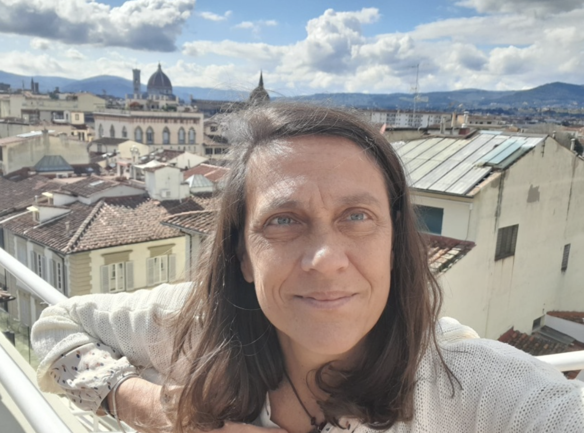 Donna in primo piano con i tetti di una cittá sullo sfondo.